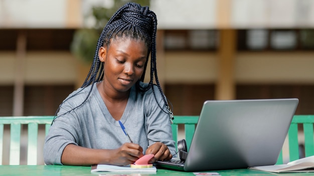 Studente del colpo medio che studia con il computer portatile