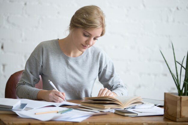 Studente femminile che esegue un compito scritto in un copybook