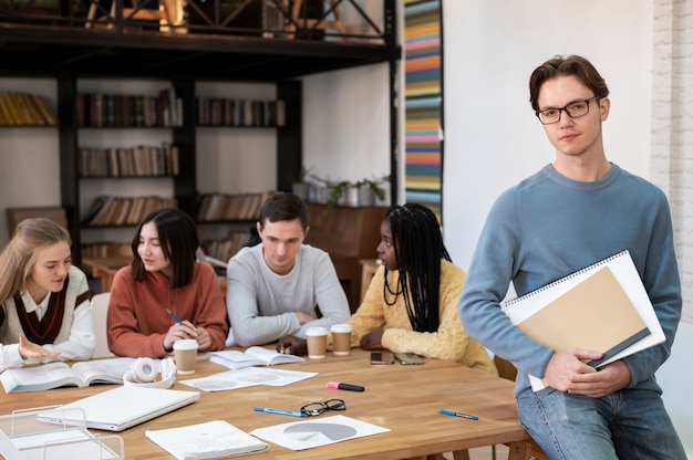 Studente in posa durante una sessione di studio di gruppo con i colleghi