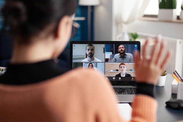 Studente in una videochiamata di gruppo sul laptop. Libero professionista che lavora da casa e incontra i colleghi online. Collega che saluta lo schermo nella conferenza del team della webcam. Conversazione di briefing a distanza.