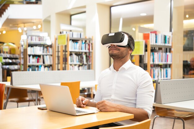 Studente maschio adulto felice che gode dell'esperienza di VR