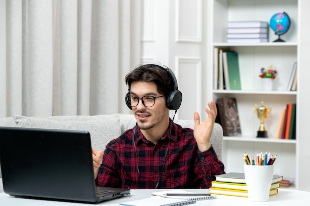 Studente online giovane ragazzo in camicia a quadri con gli occhiali che studia al computer parlando in video