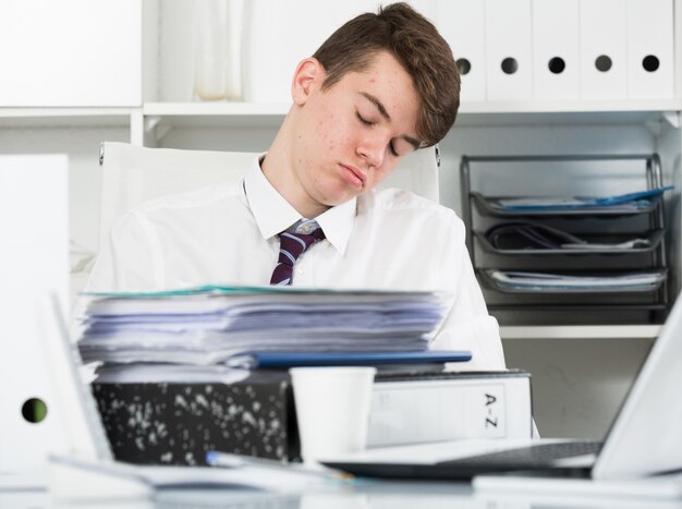 Studente stanco di lavorare e dormire in ufficio