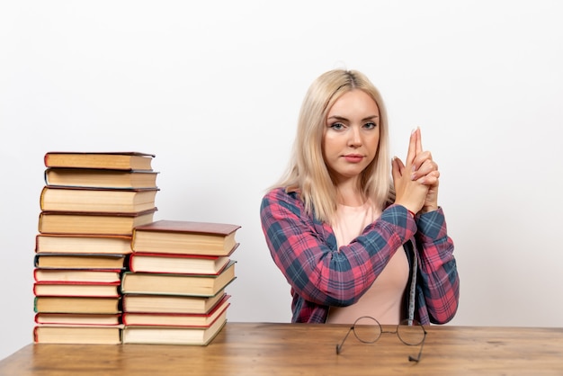 studentessa appena seduta con i libri in pistola tenendo la posa su bianco