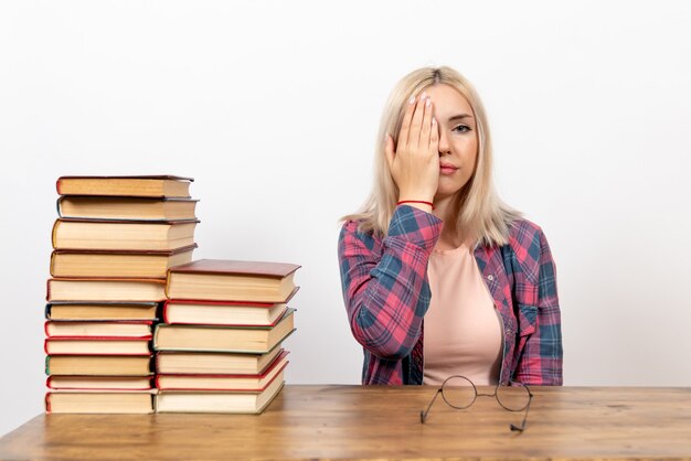 studentessa appena seduta con libri su bianco