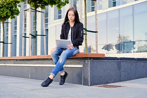 Studentessa bruna che utilizza tablet PC su una strada cittadina.