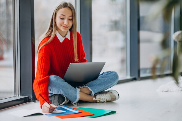 Studentessa che studia sul computer dalla finestra