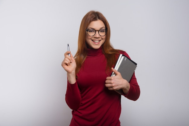 Studentessa contenta con i libri di testo e la penna