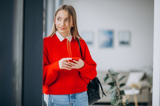 Studentessa in maglione rosso facendo uso del telefono