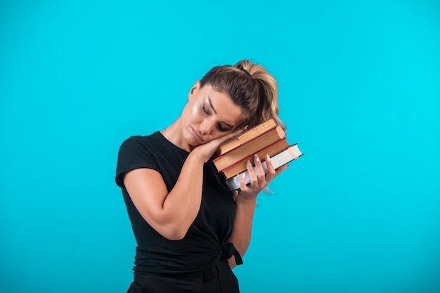 Studentessa in possesso di un pesante stock di libri e ascoltandoli.