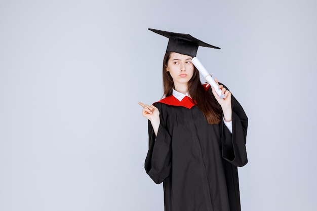 Studentessa laureata in abito con in piedi certificato universitario. Foto di alta qualità