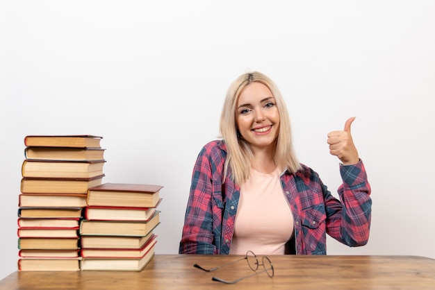 studentessa seduta con diversi libri sul pavimento bianco leggendo il libro biblioteca studentesca scuola worm