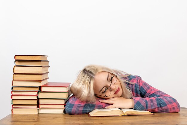 studentessa seduta con i libri sensazione di stanchezza e dormire su bianco