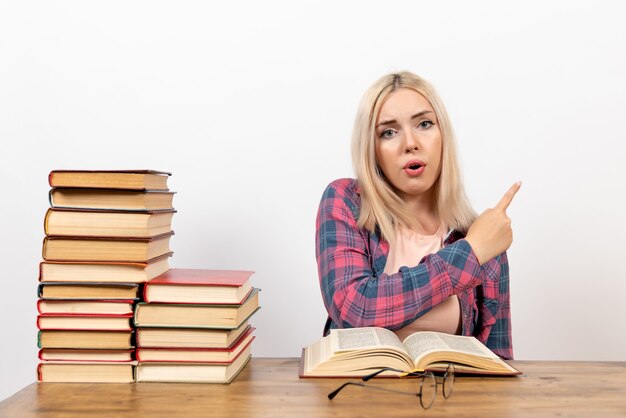 studentessa seduta con libri e lettura su bianco