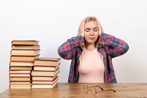 studentessa seduta con libri e posa su bianco