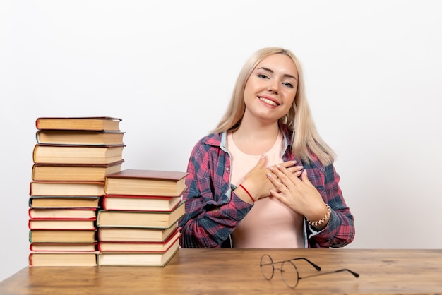 studentessa seduta con libri e posa su bianco