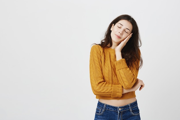 Studentessa sognante e assonnata sdraiata sul palmo con gli occhi chiusi e sorridente, sognando ad occhi aperti