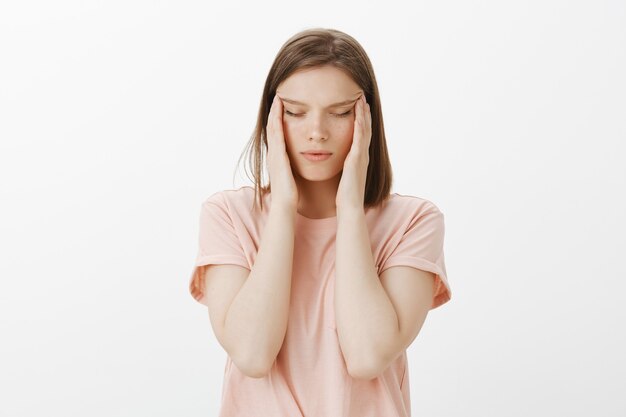 Studentessa stanca con insonnia, sfregamento delle tempie sulla testa e sguardo esausto