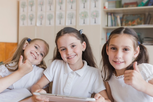 Studentesse con tablet gesticolano thumb-up