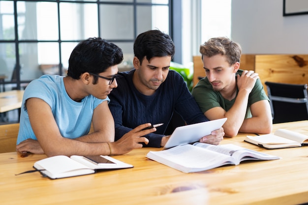 Studenti concentrati che utilizzano compressa e discutono di informazioni