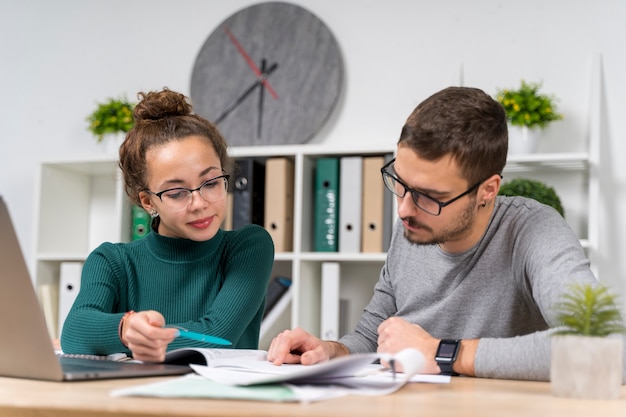 Studenti di tiro medio con gli occhiali in biblioteca