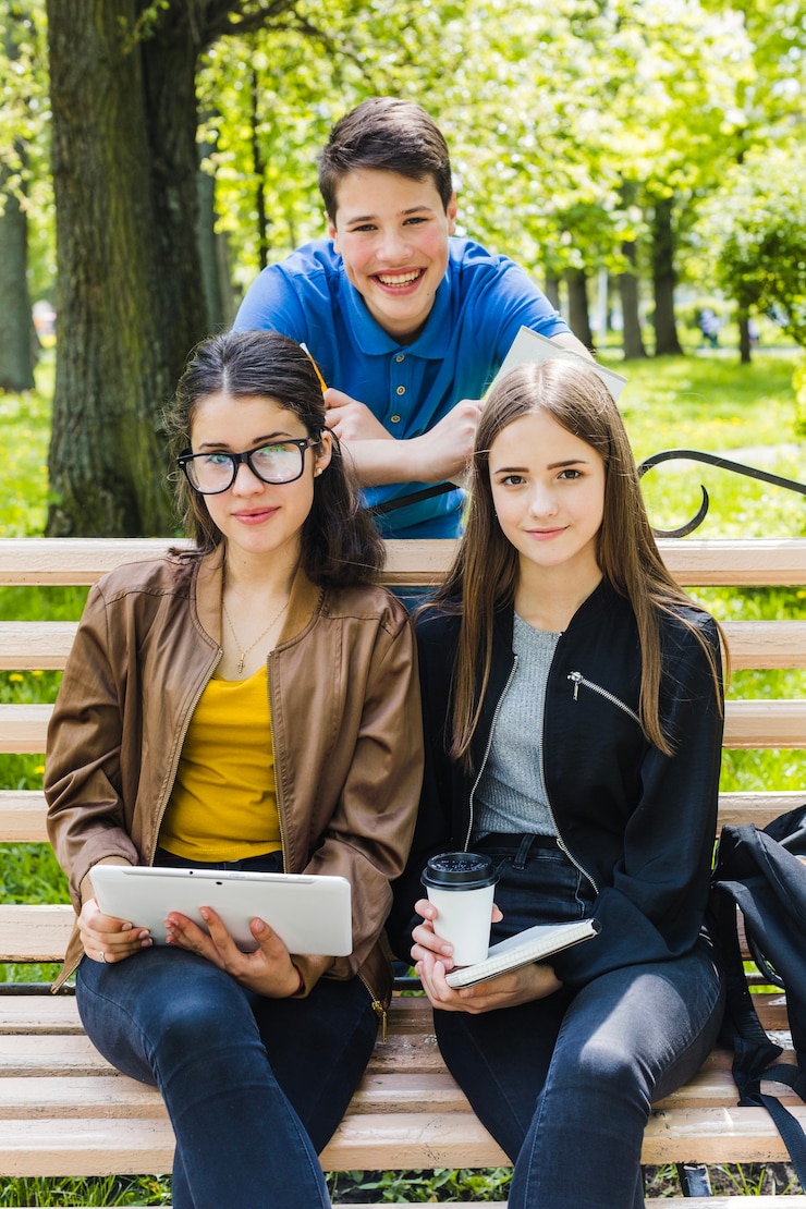 Foto gratuito studenti felici che presentano sulla panchina