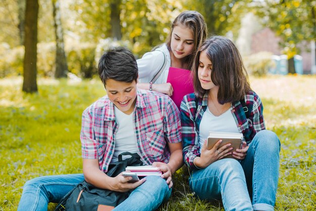 Studenti nel parco guardando telefono