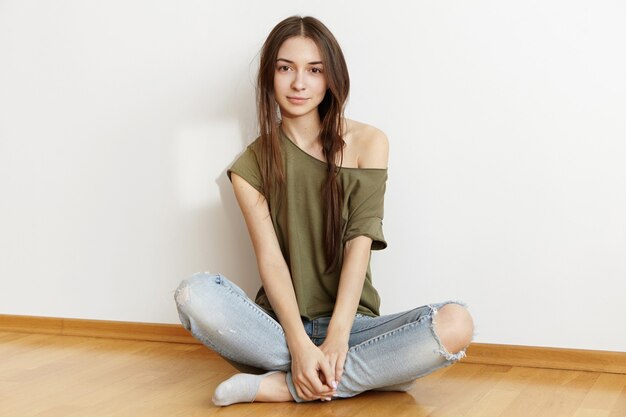 Studio shot di affascinante donna adolescente con acconciatura disordinato vestito con un top oversize