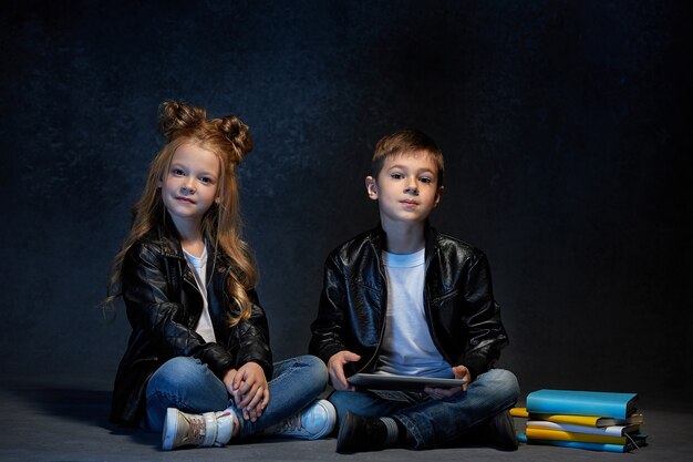 Studio shot di due bambini con tablet seduto al pavimento