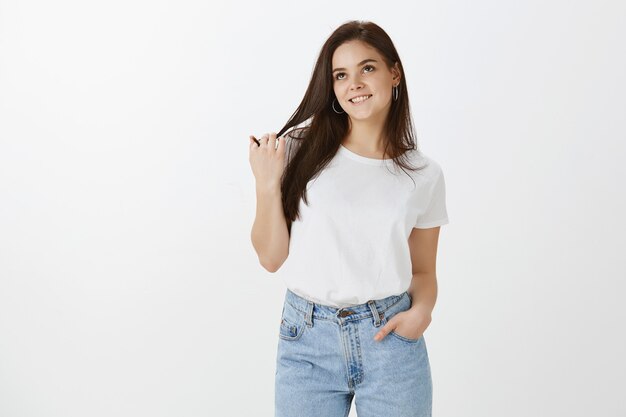 Studio shot di elegante giovane donna in posa contro il muro bianco