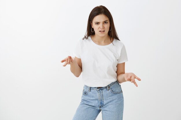 Studio shot di irritato giovane donna in posa contro il muro bianco