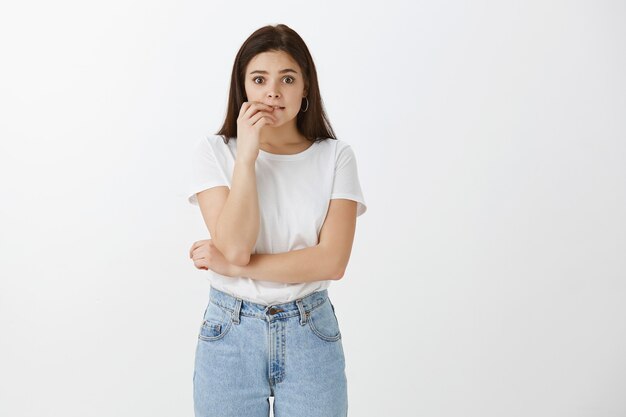 Studio shot di preoccupata giovane donna in posa contro il muro bianco