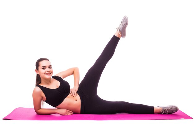 Studio shot di una giovane donna adatta facendo esercizi di yoga isolati su sfondo bianco
