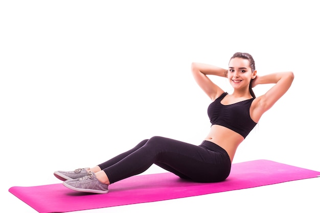 Studio shot di una giovane donna adatta facendo esercizi di yoga isolati su sfondo bianco