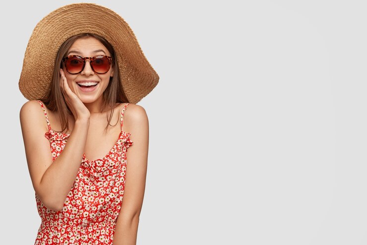 Foto gratuito studio vista di donna allegra con sorriso a trentadue denti, indossa occhiali da sole alla moda, cappello di paglia