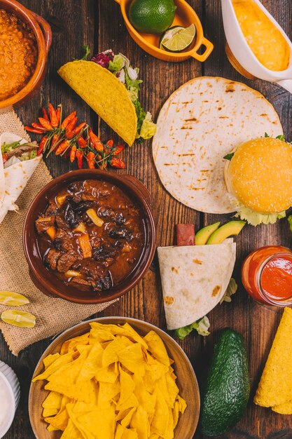 Stufato di manzo; tortilla; gustosi nachos messicani; peperoncini rossi; hamburger e avocado sul tavolo marrone