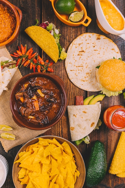 Stufato di manzo; tortilla; gustosi nachos messicani; peperoncini rossi; hamburger e avocado sul tavolo marrone