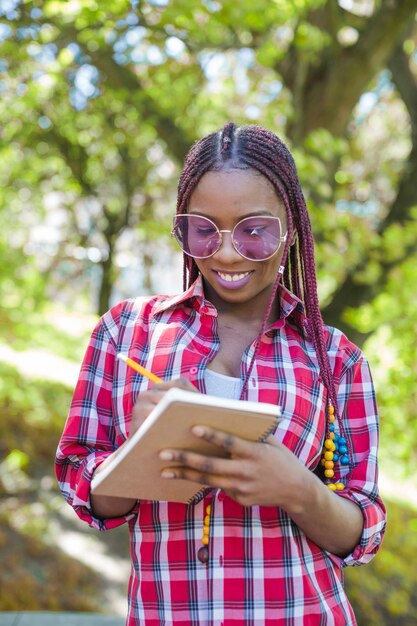 Stylish black girl scrivendo nel notebook