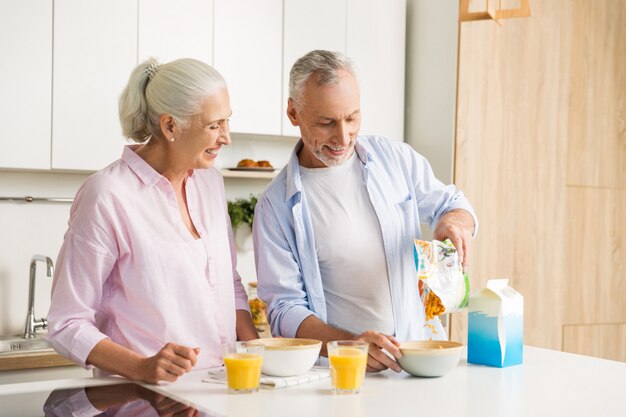 Succo bevente della famiglia amorosa allegra matura delle coppie che mangia i fiocchi di mais