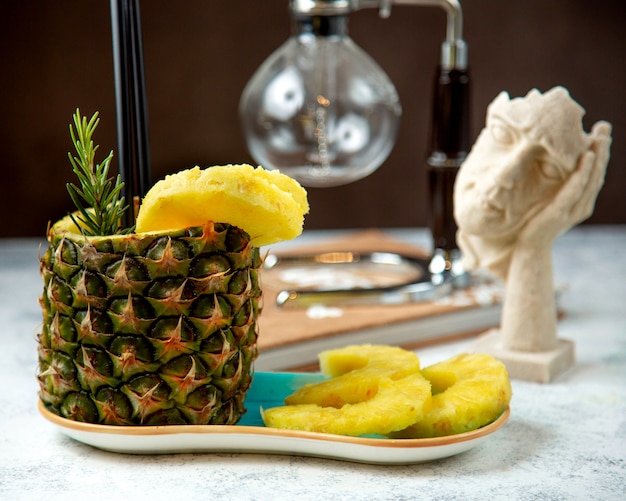 Succo d'ananas in tazza di ananas servito con fette di ananas