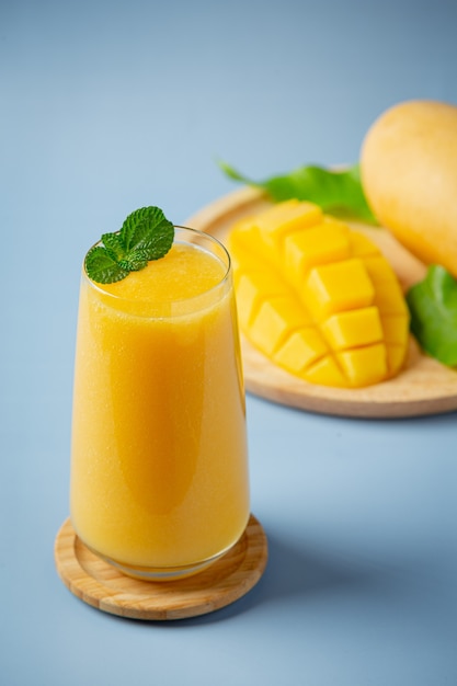 Succo di mango nel bicchiere sulla superficie blu