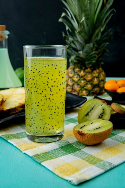 Succo e kiwi di kiwi con altri frutti sulla superficie del panno e sulla superficie nera