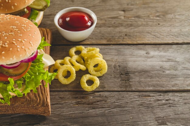 Superficie in legno con gustosi hamburger e anelli di cipolla