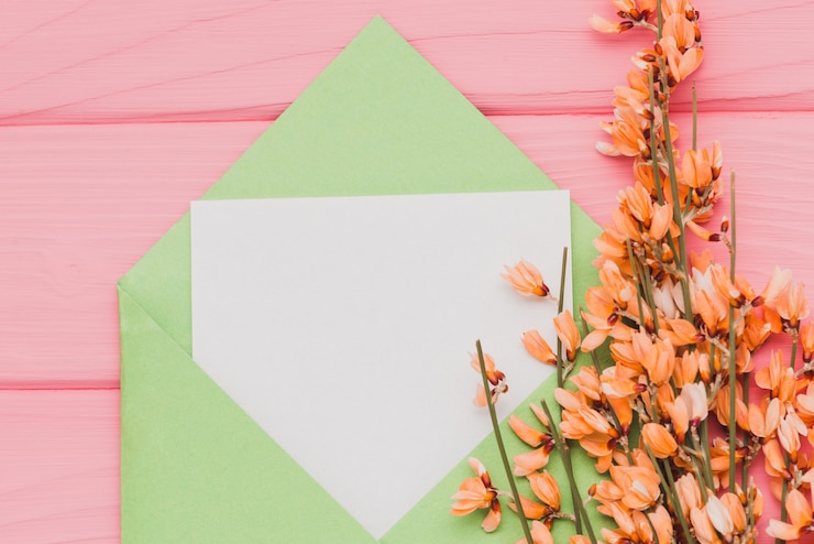 Foto gratuito superficie rosa con carta bianca e decorazione floreale