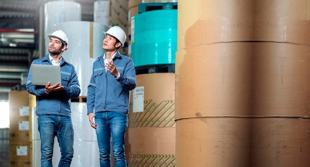 Supervisore manager ingegnere maschio lavoratore indossa la mano di lavoro uniforme utilizzare laptop stock check-in magazzino magazzino spedizione team industriale con casco di sicurezza che controlla la quantità di prodotto sullo scaffale