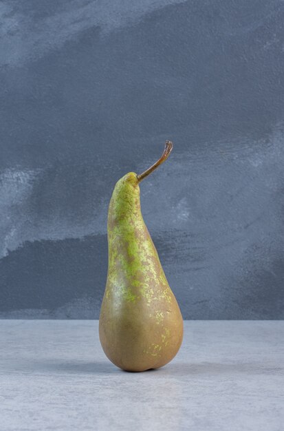 Supporto di pera fresca verde su sfondo grigio.