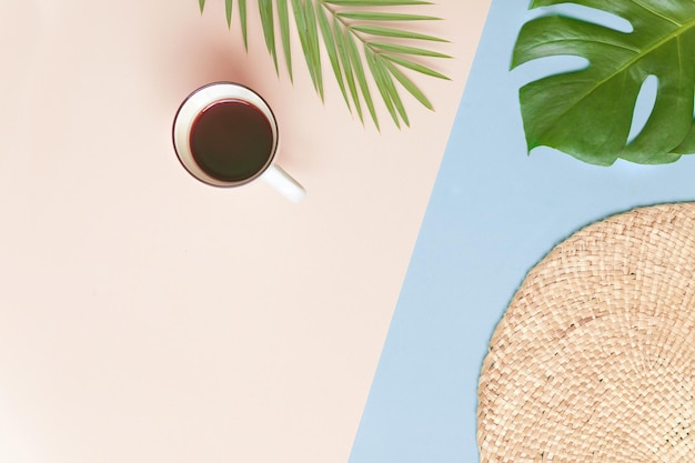 Supporto rotondo in vimini e foglie di palma tropicali con una tazza di caffè su sfondo rosa Concetto di stile Fltlay con posto del testo
