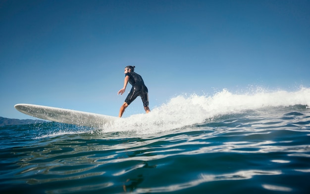 Surfer riding wave in vista di luce diurna lunga