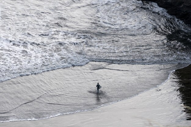 Surfista che cammina nel mare mentre tiene una tavola da surf in Nuova Zelanda