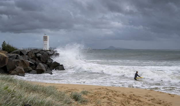 Surfista con una tavola da surf gialla che gode delle onde della Sunshine Coast dell'Australia